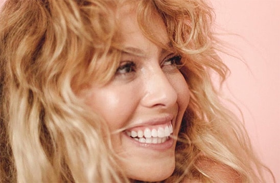 Smiling woman with wavy hair against pink background