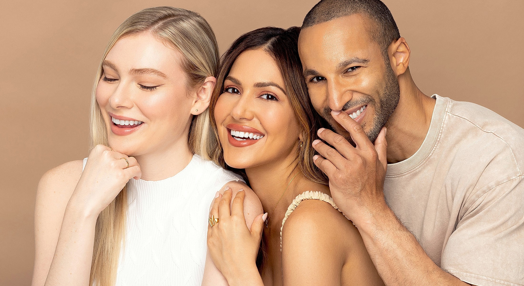 Three smiling individuals with diverse hairstyles and expressions.